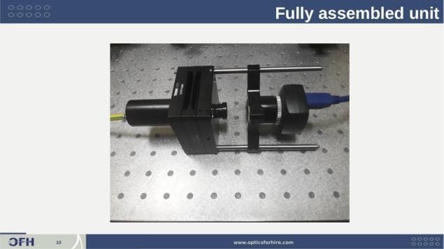 Fully assembled acceptance test fixture with IDS UI-1480 camera attached showing liquid-immersion Ronchi ruling assembly, central lens holder, and camera on right arm